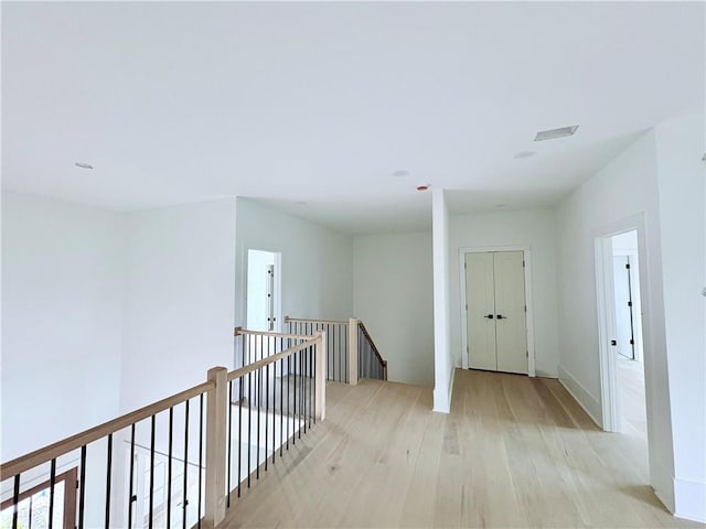 corridor featuring an upstairs landing and light wood-style flooring