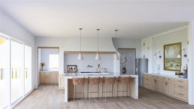 kitchen with freestanding refrigerator, light countertops, tasteful backsplash, light wood-style flooring, and a breakfast bar