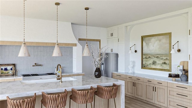 kitchen featuring stainless steel fridge with ice dispenser, a breakfast bar, light stone counters, light wood-style floors, and tasteful backsplash