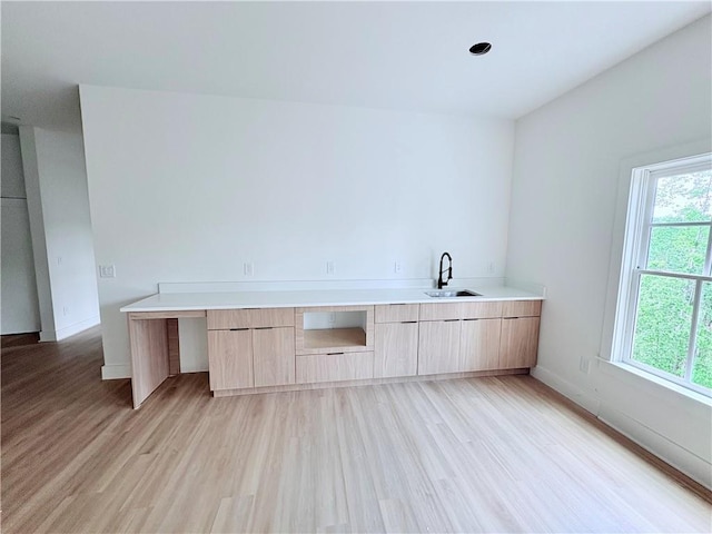 laundry area featuring a sink, light wood-type flooring, and baseboards