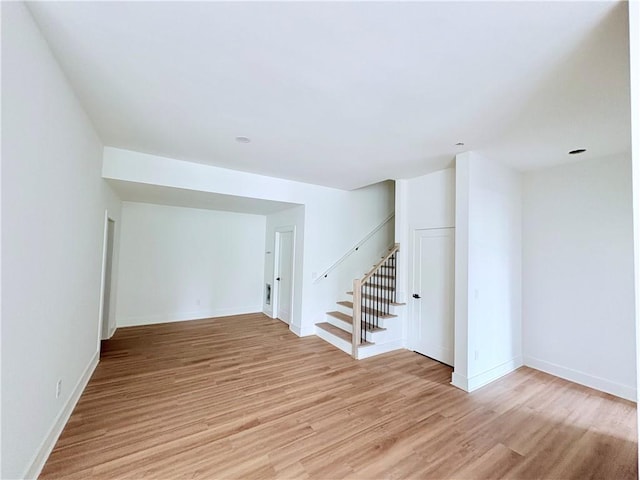 basement featuring stairway, light wood-style floors, and baseboards