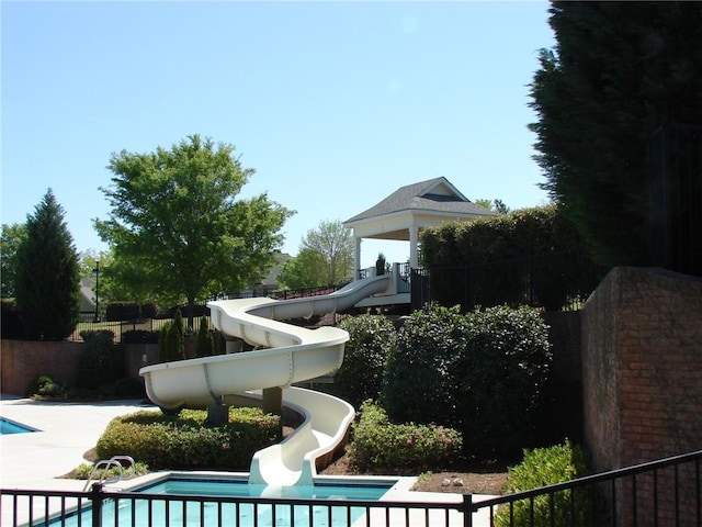 view of pool with a water slide and fence