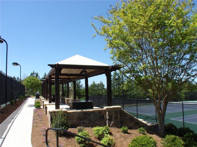view of home's community with a gazebo, a tennis court, and fence