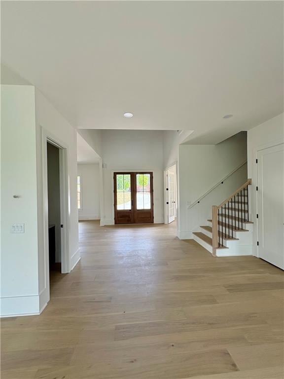 unfurnished living room featuring stairs, light wood-style flooring, baseboards, french doors, and recessed lighting