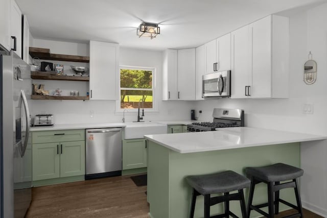 3142 Chamblee Gap Rd, Cumming, GA 30040 - kitchen featuring stainless steel appliances, green cabinetry, a sink, a peninsula, and a kitchen bar