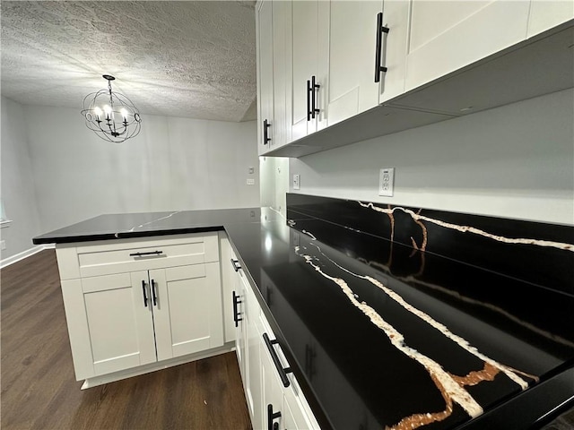 kitchen featuring dark wood-type flooring, a textured ceiling, kitchen peninsula, pendant lighting, and white cabinets