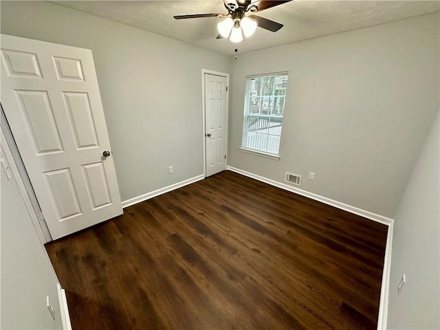 unfurnished bedroom with dark wood-type flooring, a textured ceiling, and ceiling fan