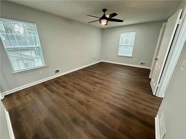 unfurnished bedroom with ceiling fan, dark hardwood / wood-style floors, and multiple windows