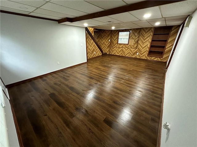 basement with dark hardwood / wood-style flooring and wood walls