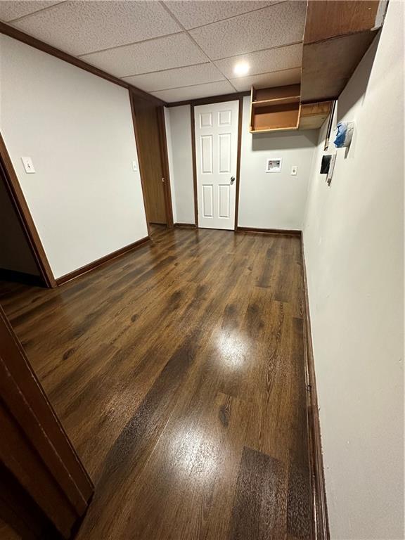 empty room featuring dark wood-type flooring and a drop ceiling