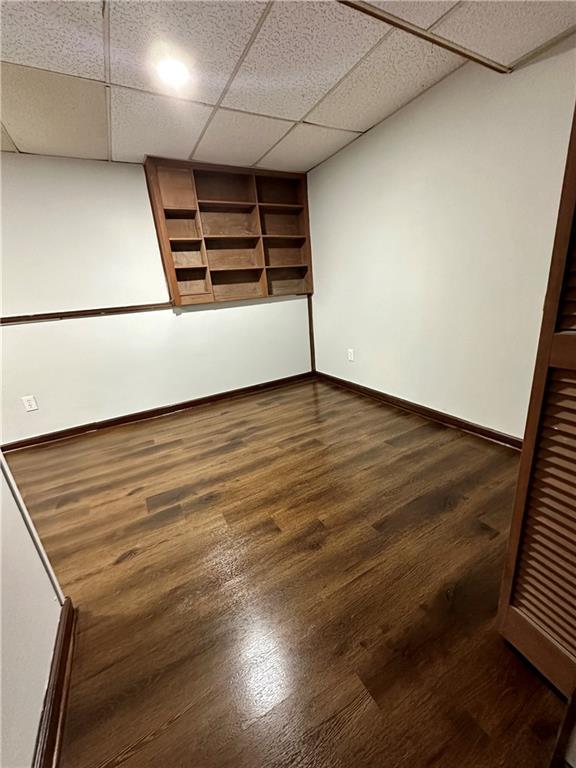 interior space with dark wood-type flooring and a paneled ceiling