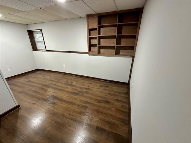 spare room featuring a drop ceiling and dark wood-type flooring