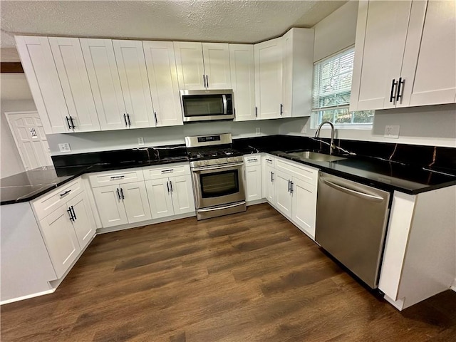 kitchen featuring sink, dark wood-type flooring, stainless steel appliances, a textured ceiling, and white cabinets