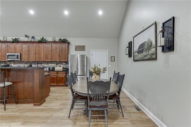 dining room featuring light hardwood / wood-style flooring and vaulted ceiling