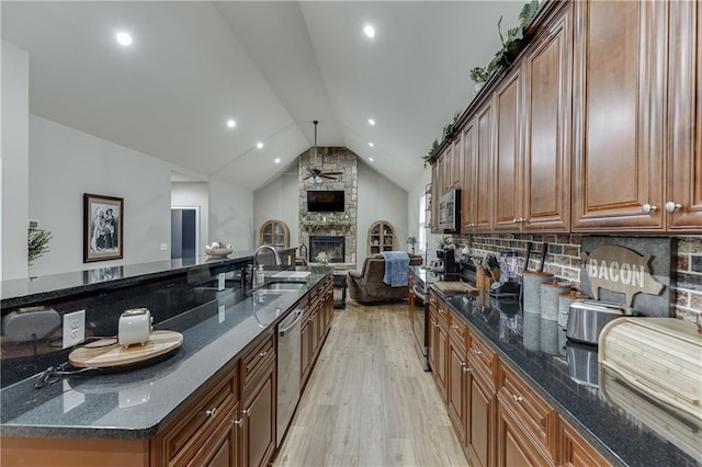 kitchen with light hardwood / wood-style flooring, ceiling fan, dark stone countertops, stainless steel appliances, and a fireplace