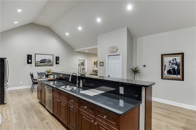 kitchen with a kitchen island with sink, sink, lofted ceiling, and light wood-type flooring