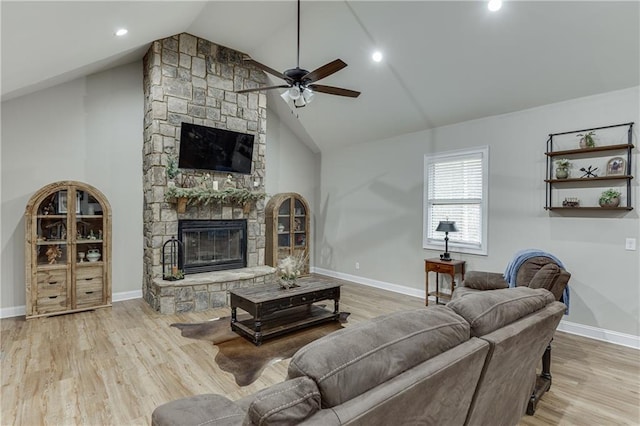 living room with a stone fireplace, high vaulted ceiling, ceiling fan, and light wood-type flooring