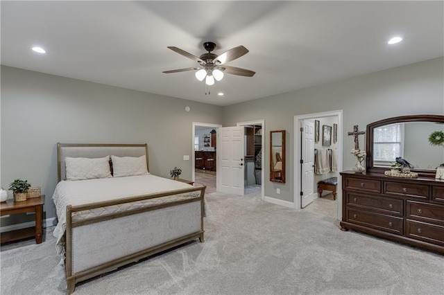 bedroom featuring connected bathroom, a spacious closet, light colored carpet, and ceiling fan