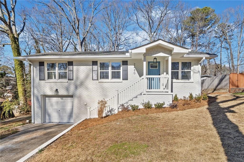 view of front of home with a garage, driveway, fence, and brick siding