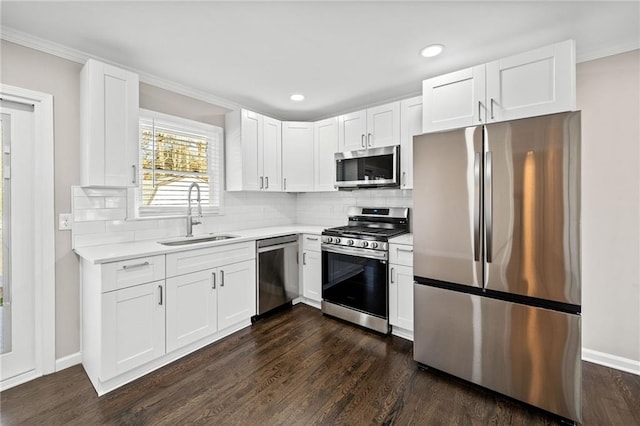 kitchen with sink, white cabinetry, appliances with stainless steel finishes, dark hardwood / wood-style floors, and decorative backsplash