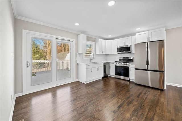 kitchen featuring appliances with stainless steel finishes, tasteful backsplash, white cabinetry, sink, and dark wood-type flooring