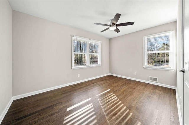 empty room with ceiling fan, a healthy amount of sunlight, and dark hardwood / wood-style flooring