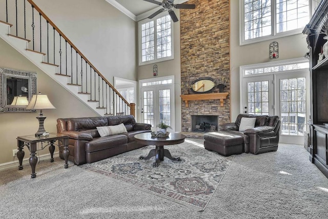 living room with baseboards, carpet floors, stairs, a stone fireplace, and french doors