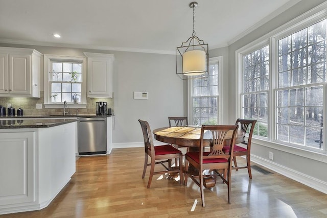 dining area with light wood-style flooring, baseboards, visible vents, and ornamental molding