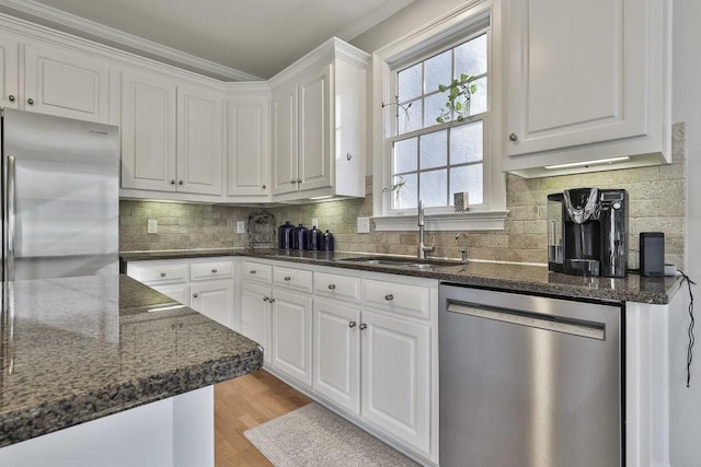 kitchen with light wood finished floors, white cabinets, appliances with stainless steel finishes, and a sink