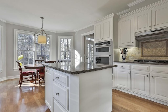 kitchen with a kitchen island, under cabinet range hood, double oven, black stovetop, and light wood-type flooring