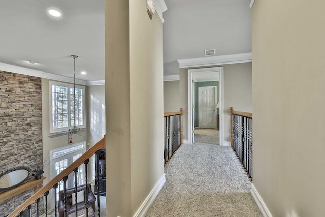 hall featuring visible vents, crown molding, baseboards, carpet floors, and an upstairs landing