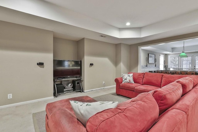 living room with a raised ceiling, visible vents, baseboards, and carpet floors