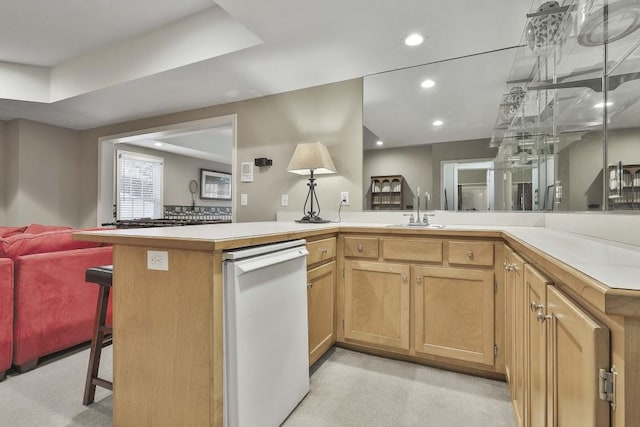 kitchen with a kitchen bar, a sink, open floor plan, white dishwasher, and light countertops