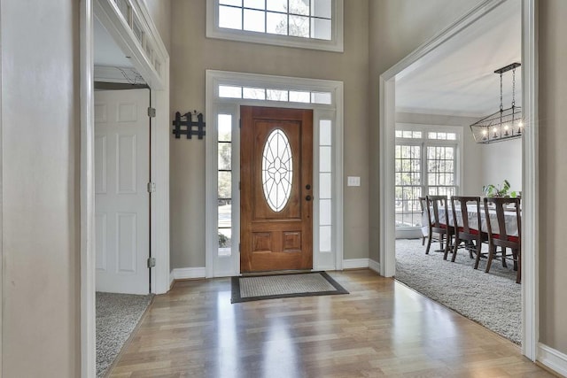 entrance foyer featuring baseboards, an inviting chandelier, and wood finished floors