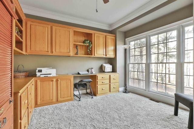 office featuring visible vents, crown molding, carpet floors, built in desk, and a ceiling fan