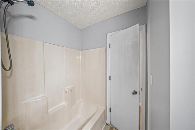 full bathroom with a textured ceiling and shower / bath combination