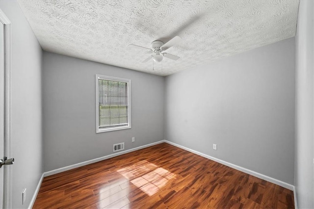 unfurnished room with a textured ceiling, baseboards, visible vents, wood finished floors, and ceiling fan