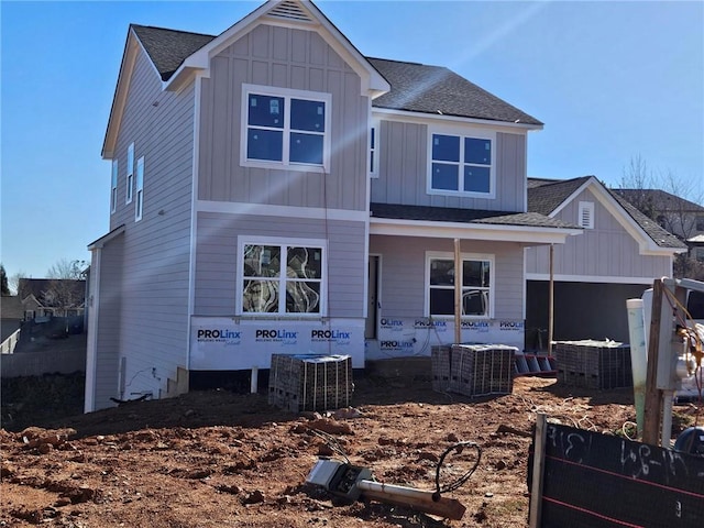 view of front of house featuring board and batten siding, covered porch, a shingled roof, and central AC unit