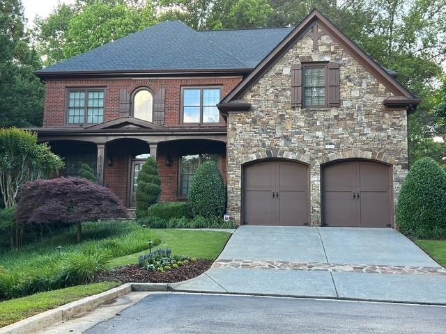 1984 Mendenhall Cir, Atlanta, GA 30341 - view of front of home with a garage, stone siding, driveway, and roof with shingles