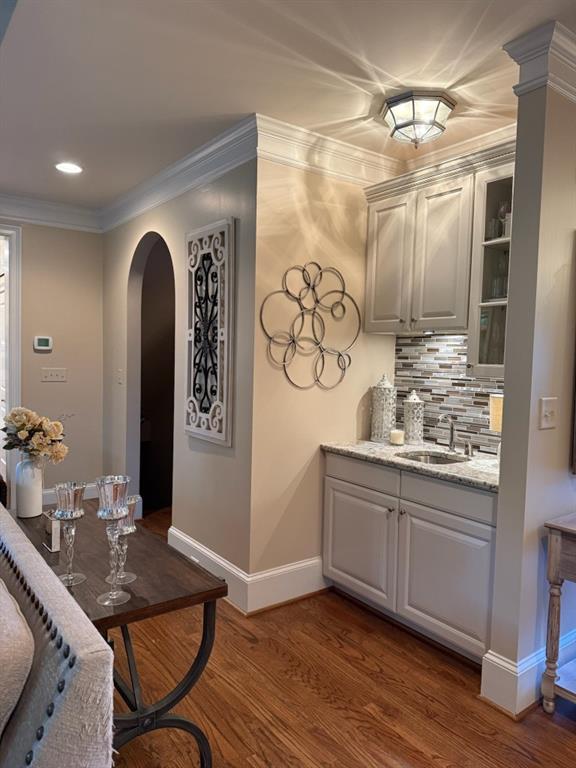 1984 Mendenhall Cir, Atlanta, GA 30341 - bar area featuring arched walkways, a sink, baseboards, dark wood-style floors, and tasteful backsplash