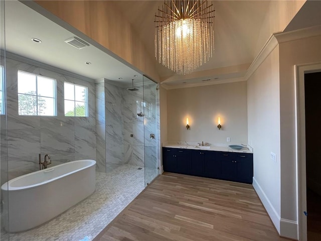 bathroom featuring a notable chandelier, wood-type flooring, vanity, and plus walk in shower