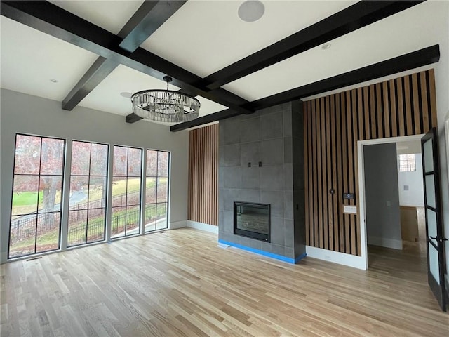 unfurnished living room featuring a fireplace, beamed ceiling, coffered ceiling, a notable chandelier, and light hardwood / wood-style floors