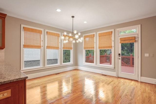 unfurnished dining area featuring light wood-type flooring, a chandelier, and ornamental molding