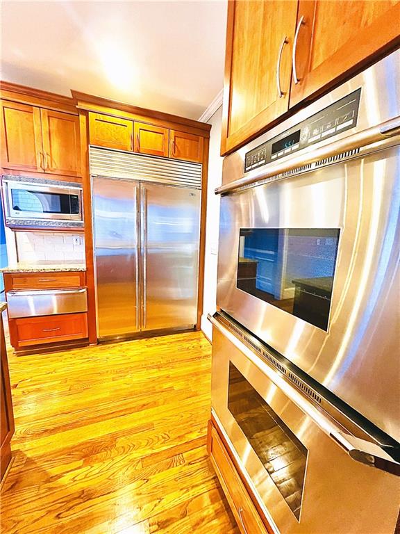 kitchen featuring ornamental molding, light hardwood / wood-style floors, and built in appliances