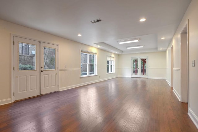 spare room featuring dark wood-type flooring, a raised ceiling, and french doors