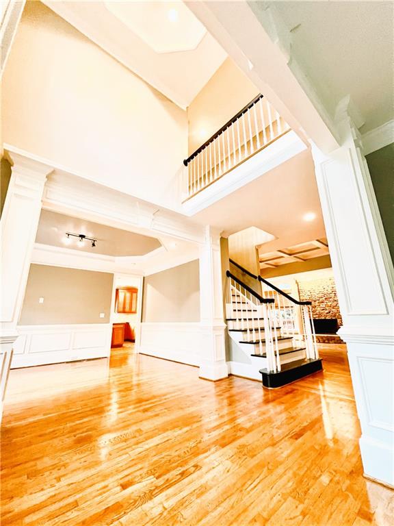 staircase featuring a high ceiling, wood-type flooring, and crown molding