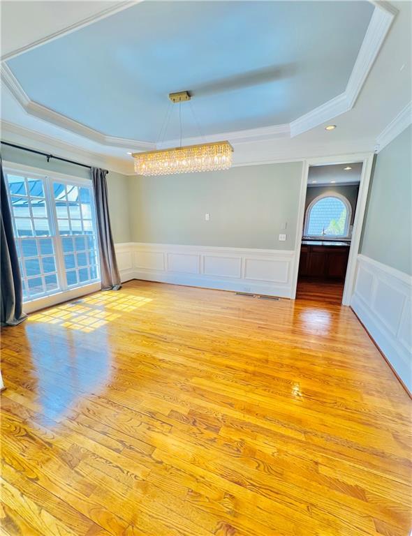 spare room featuring a tray ceiling, ornamental molding, and light hardwood / wood-style flooring