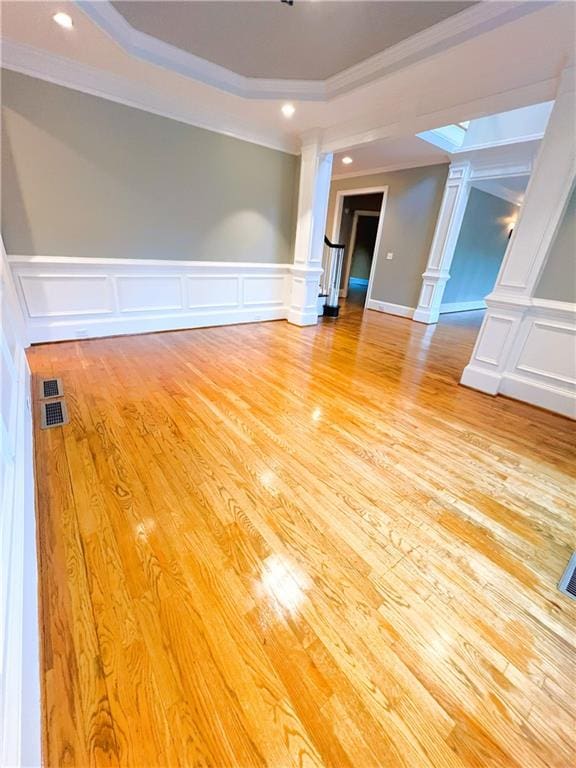 unfurnished room featuring a tray ceiling, ornamental molding, and light hardwood / wood-style floors