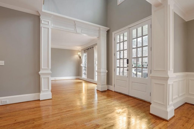 entrance foyer featuring light wood-type flooring, ornate columns, crown molding, and french doors