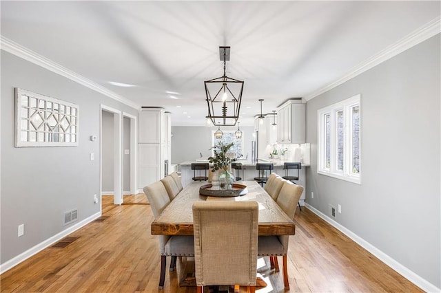 dining room with baseboards, light wood-style floors, and crown molding